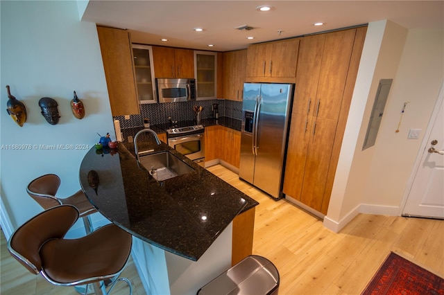 kitchen featuring light hardwood / wood-style flooring, tasteful backsplash, sink, stainless steel appliances, and electric panel