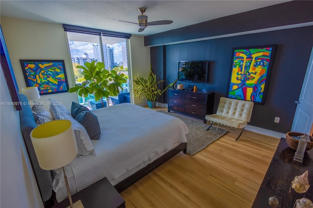 bedroom featuring floor to ceiling windows, hardwood / wood-style flooring, and ceiling fan