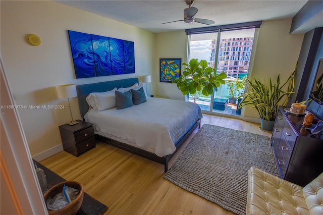 bedroom with light hardwood / wood-style floors, access to outside, floor to ceiling windows, and ceiling fan