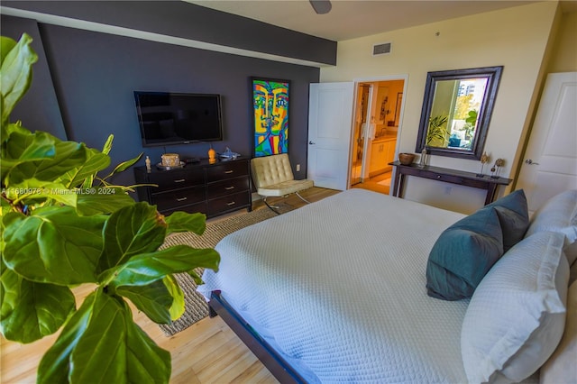 bedroom featuring hardwood / wood-style flooring and ensuite bath