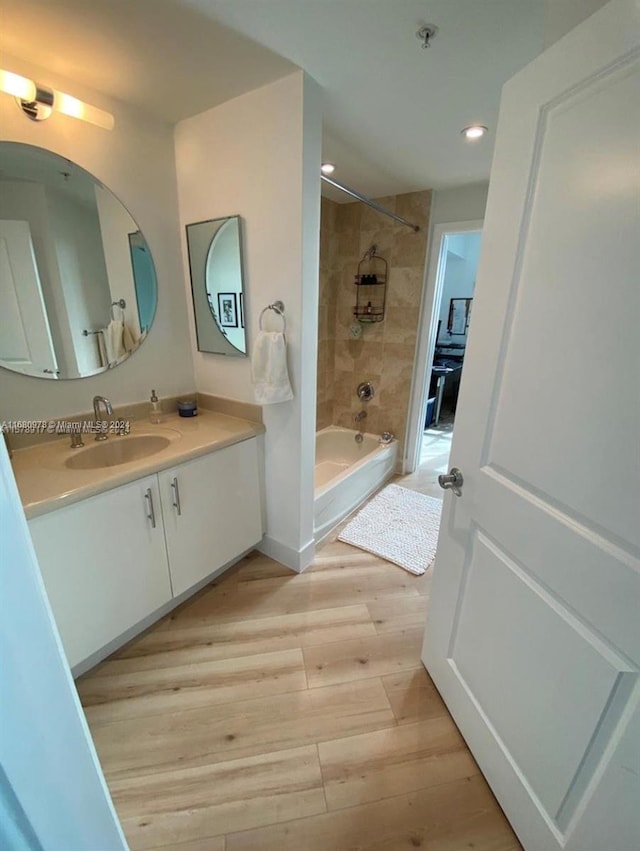 bathroom featuring vanity, hardwood / wood-style floors, and tiled shower / bath combo