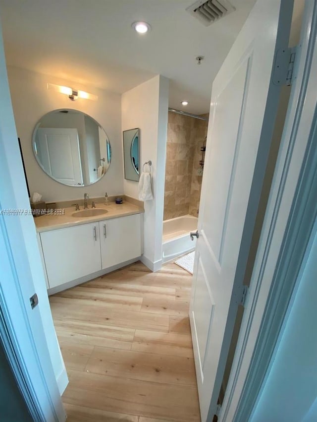 bathroom with vanity, tiled shower, and hardwood / wood-style floors