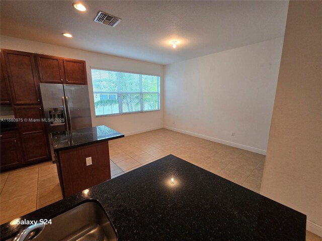 kitchen featuring kitchen peninsula, dark brown cabinets, appliances with stainless steel finishes, sink, and light tile patterned flooring