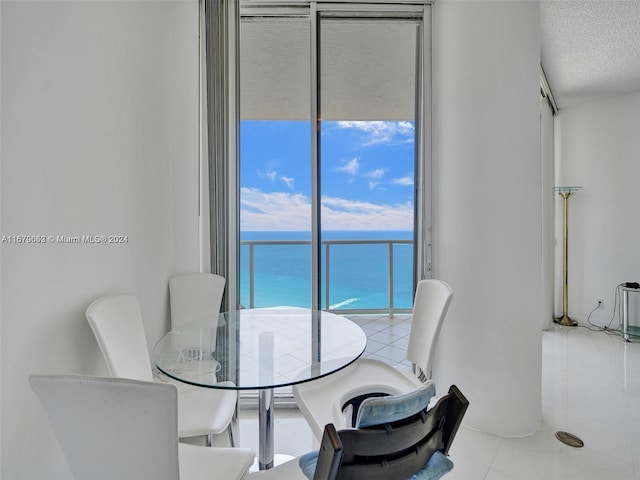 dining space with a textured ceiling, light tile patterned flooring, and a water view