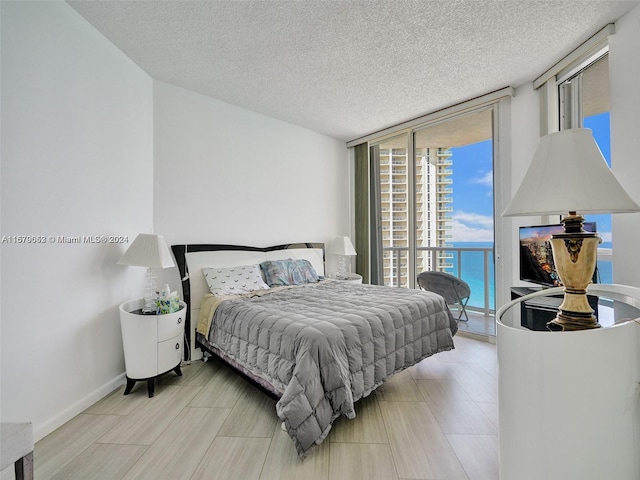 bedroom featuring a textured ceiling, access to exterior, and floor to ceiling windows