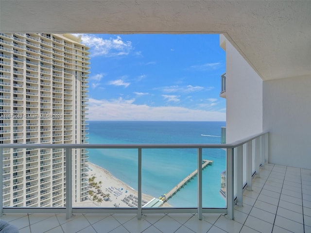 balcony featuring a view of the beach and a water view