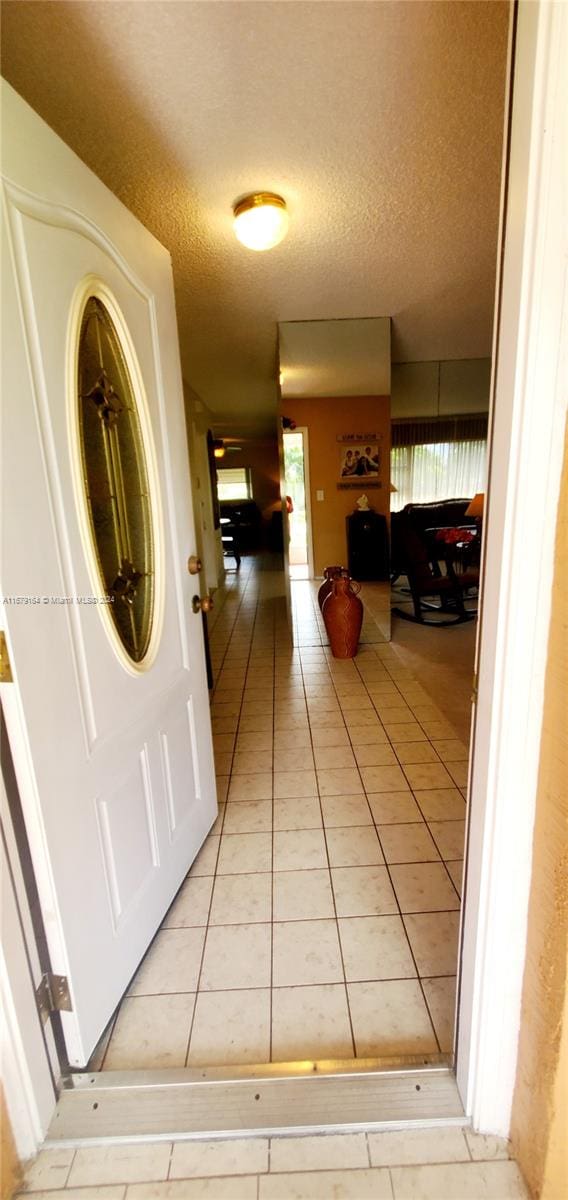 hallway with light tile patterned flooring and a textured ceiling