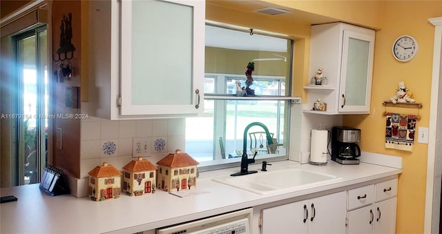 kitchen with white cabinetry, decorative backsplash, and dishwashing machine