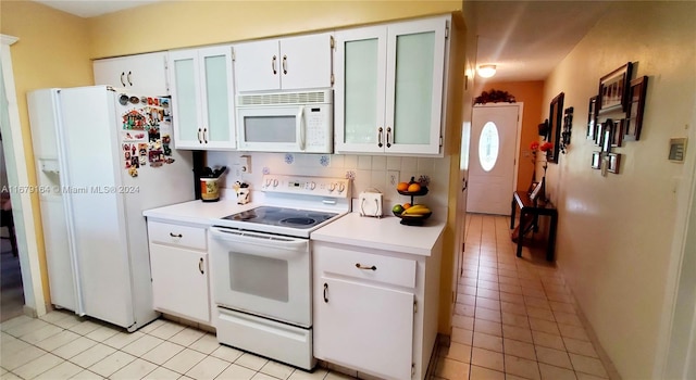 kitchen featuring white cabinetry, decorative backsplash, light tile patterned flooring, and white appliances