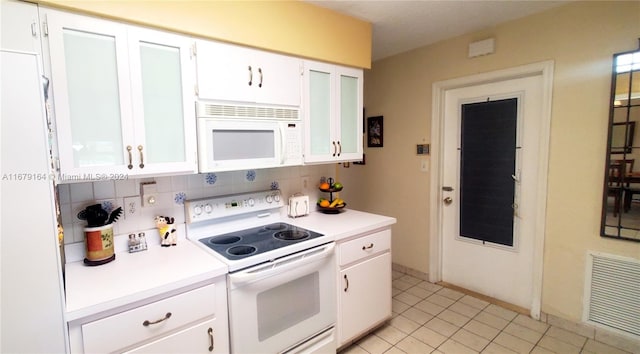 kitchen with white appliances, white cabinetry, light tile patterned floors, and backsplash