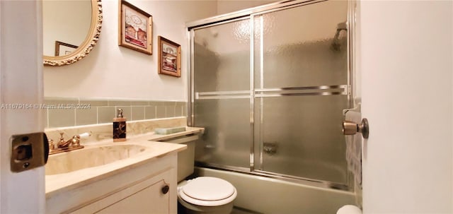 full bathroom with toilet, bath / shower combo with glass door, and vanity