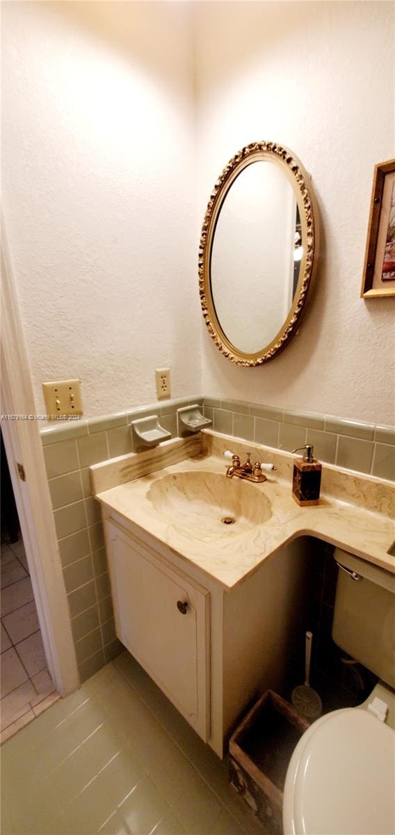 bathroom featuring vanity, tile patterned floors, toilet, and tile walls