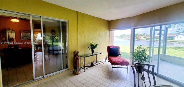 sunroom / solarium featuring a water view and ceiling fan