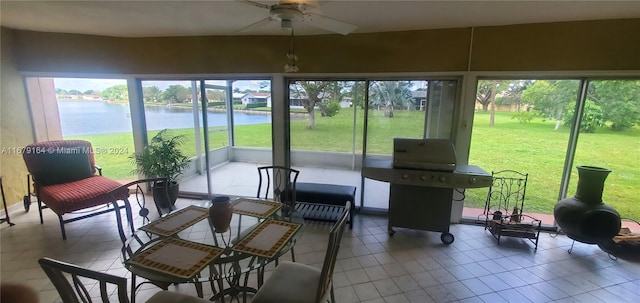 sunroom / solarium with ceiling fan and a water view