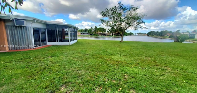 view of yard with a sunroom and a water view