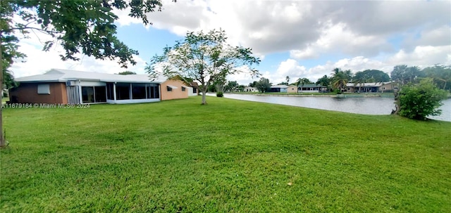 view of yard featuring a sunroom and a water view