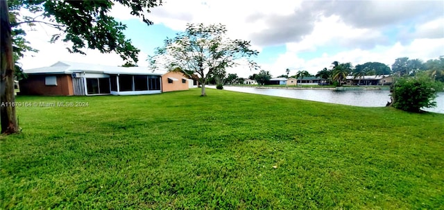 view of yard featuring a sunroom and a water view