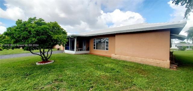 rear view of house with a sunroom and a yard