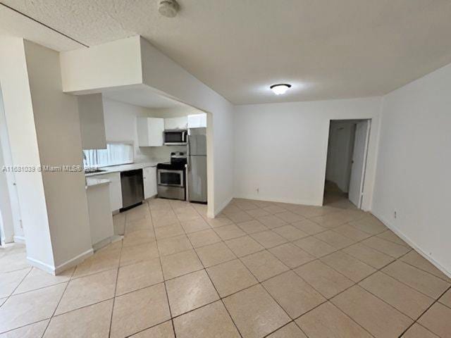 kitchen with light tile patterned flooring, white cabinetry, and stainless steel appliances