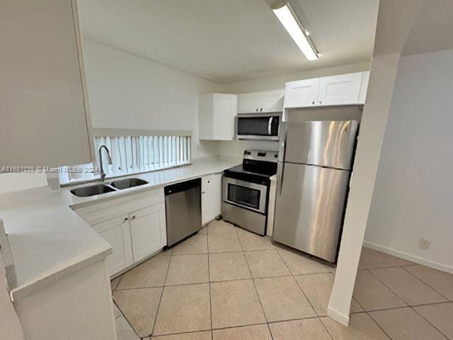 kitchen with sink, white cabinetry, stainless steel appliances, and light tile patterned flooring