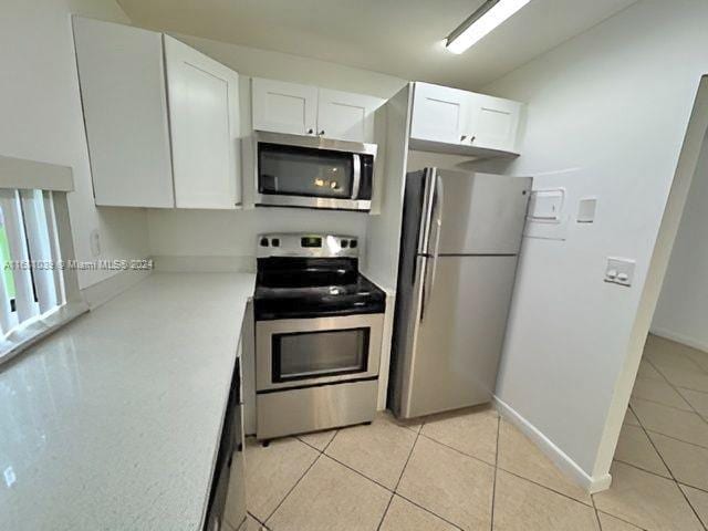 kitchen featuring white cabinets, light countertops, appliances with stainless steel finishes, and light tile patterned floors