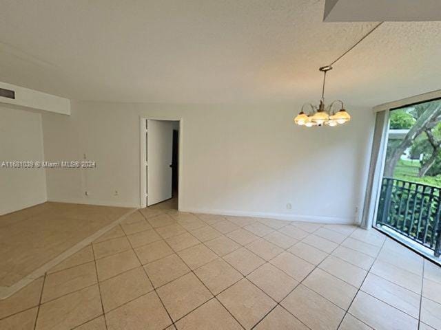 spare room with a textured ceiling, an inviting chandelier, and light tile patterned floors