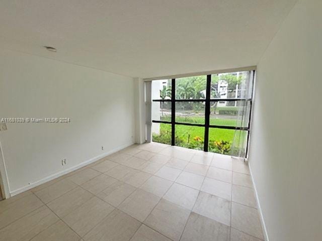 tiled empty room featuring a wall of windows