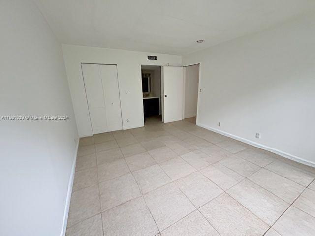 unfurnished bedroom with light tile patterned floors, baseboards, and visible vents
