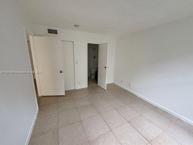 unfurnished bedroom featuring light tile patterned floors, visible vents, and baseboards