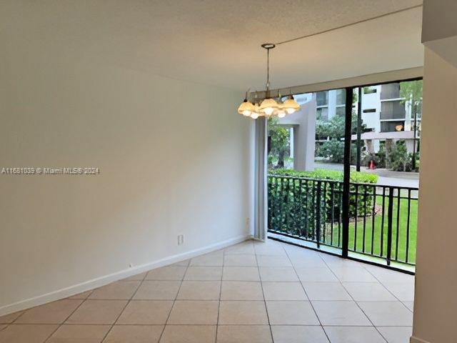 unfurnished room featuring light tile patterned floors and a chandelier