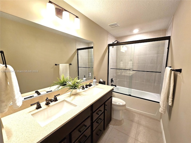 full bathroom featuring a textured ceiling, shower / bath combination with glass door, toilet, tile patterned floors, and vanity