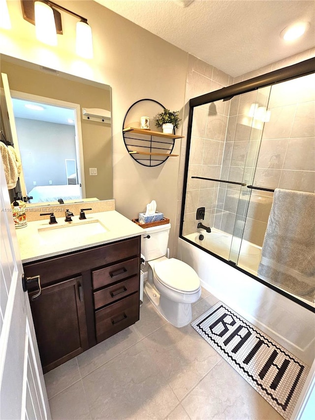 full bathroom featuring a textured ceiling, shower / bath combination with glass door, toilet, vanity, and tile patterned flooring