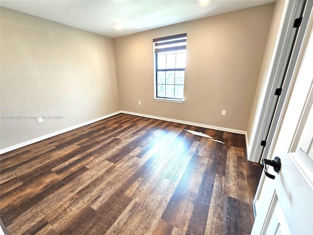 unfurnished room featuring a textured ceiling and dark hardwood / wood-style flooring