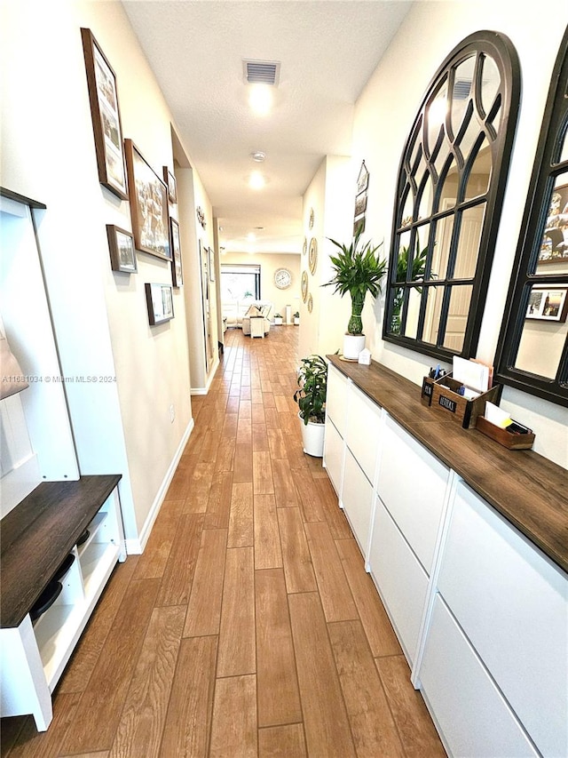 hall featuring light hardwood / wood-style floors and a textured ceiling