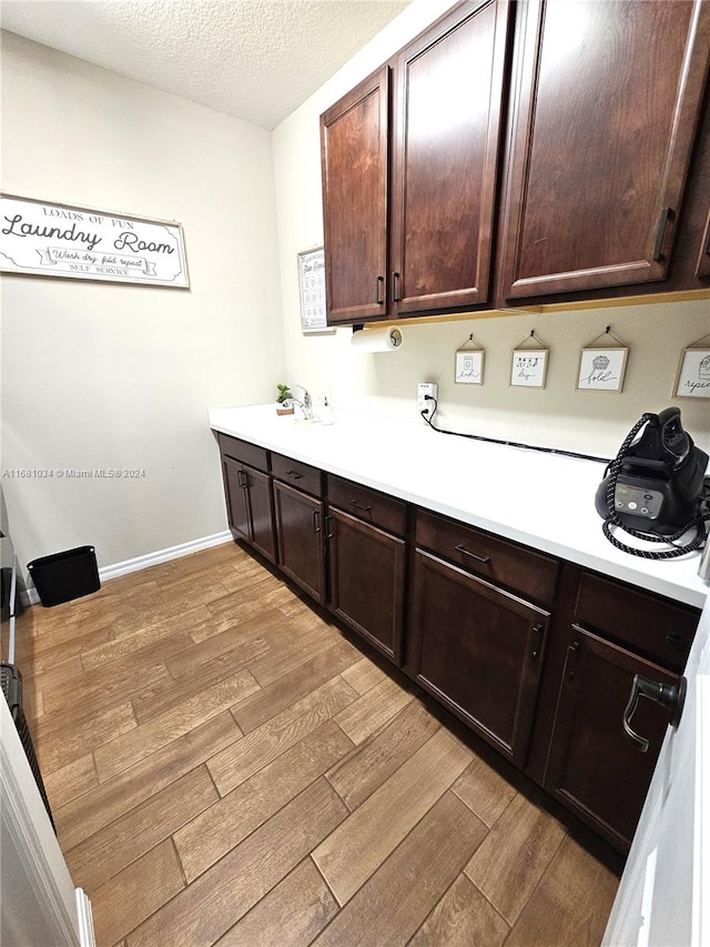 kitchen with light hardwood / wood-style floors, a textured ceiling, sink, and dark brown cabinets