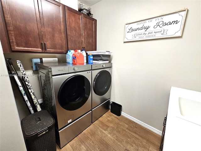 laundry room with sink, washer and dryer, light hardwood / wood-style floors, and cabinets