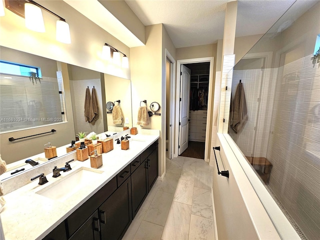 bathroom featuring vanity, a textured ceiling, and tiled shower