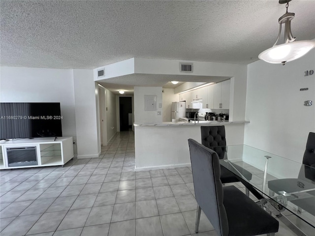 kitchen featuring kitchen peninsula, white cabinetry, a textured ceiling, white fridge, and decorative light fixtures