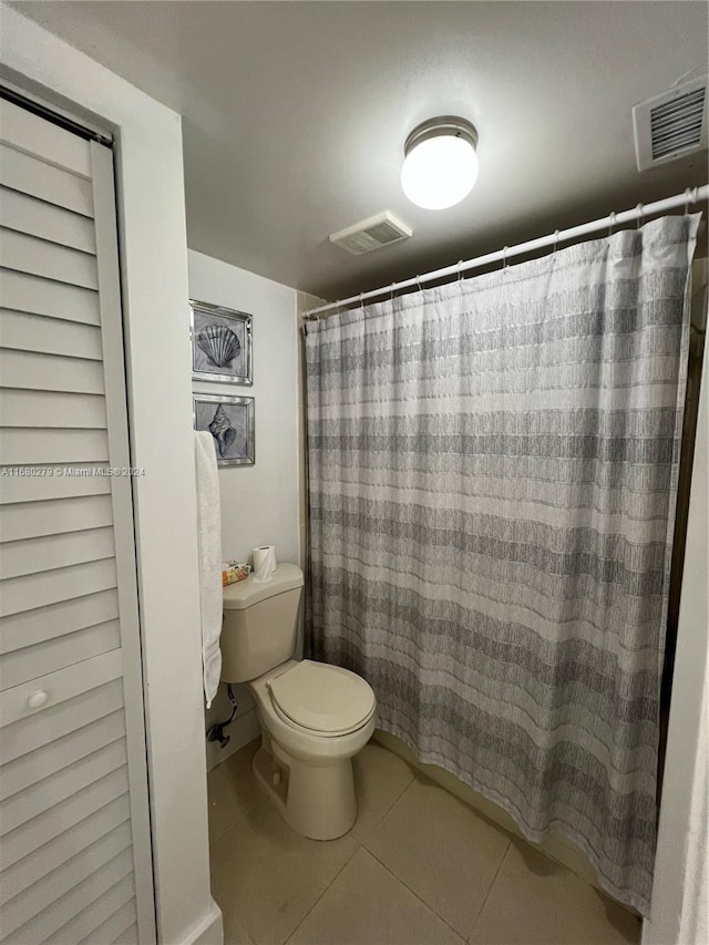 bathroom with tile patterned floors, a shower with curtain, and toilet