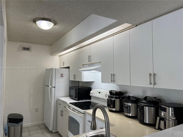 kitchen with white appliances, light tile patterned flooring, sink, a textured ceiling, and white cabinetry