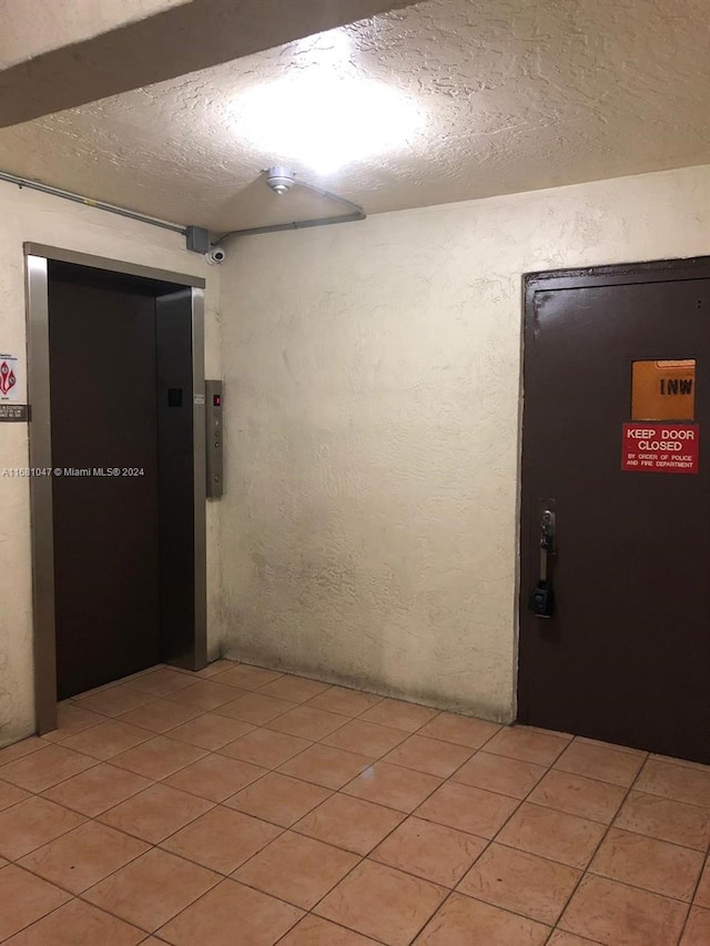 hallway featuring light tile patterned floors and elevator