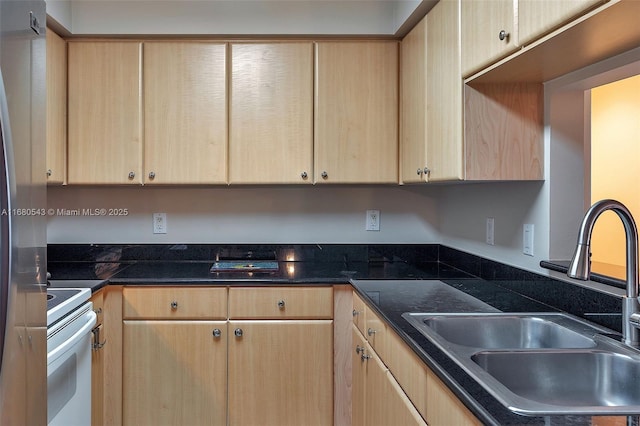 kitchen with electric stove, sink, light brown cabinetry, and dark stone countertops