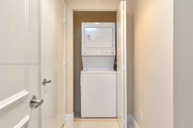 clothes washing area featuring light tile patterned flooring and stacked washer / drying machine