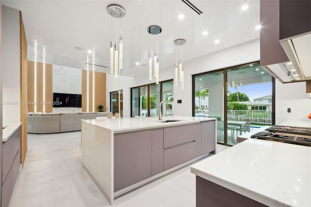 kitchen featuring gray cabinetry, a large island with sink, sink, hanging light fixtures, and light tile patterned floors