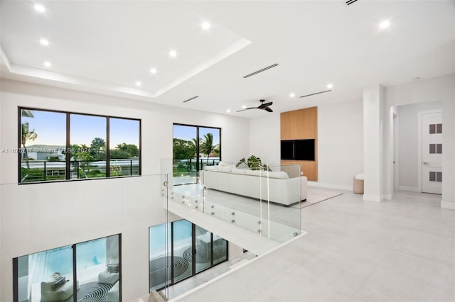 living room with ceiling fan and a tray ceiling