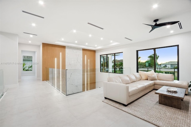 living room featuring ceiling fan and a raised ceiling