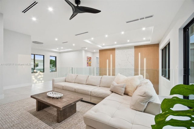 living room with a tray ceiling and ceiling fan