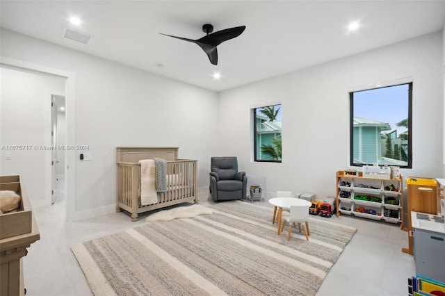 bedroom featuring multiple windows, a nursery area, and ceiling fan