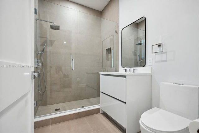 bathroom with vanity, a shower with shower door, toilet, and tile patterned floors