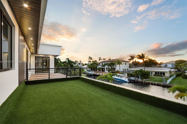 yard at dusk featuring a water view and a balcony